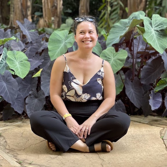 Sam sitting in front of big leaves at the Inhotim art museum in Brazil.